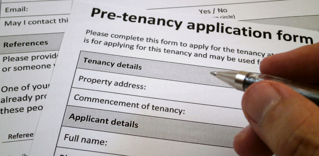 Property Management Close-up of a hand filling out a pre-tenancy application form, focusing on sections for tenancy and applicant details